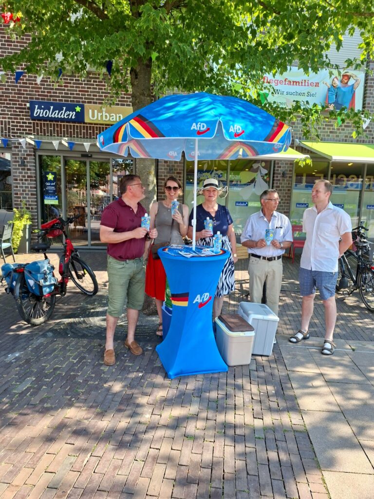 AfD-Infostand unter einem Sonnenschirm mit Besuchern und Wassereis in Dülmen